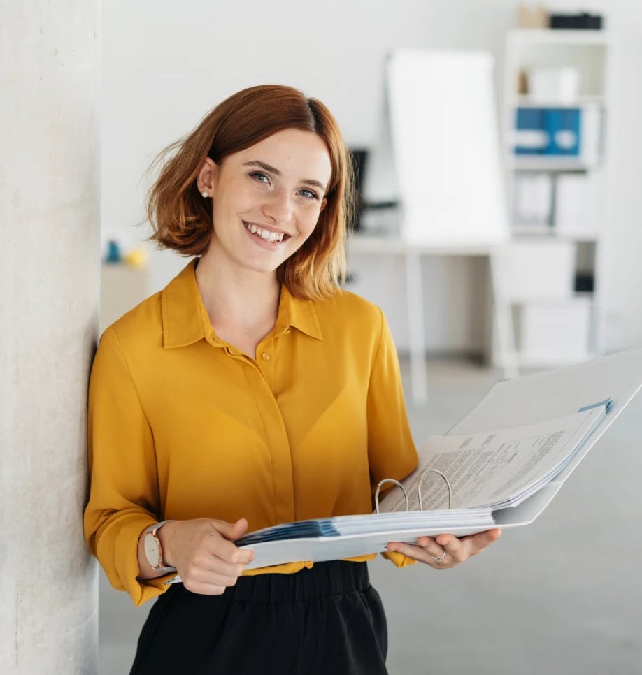 Woman smiling holding a paper binder