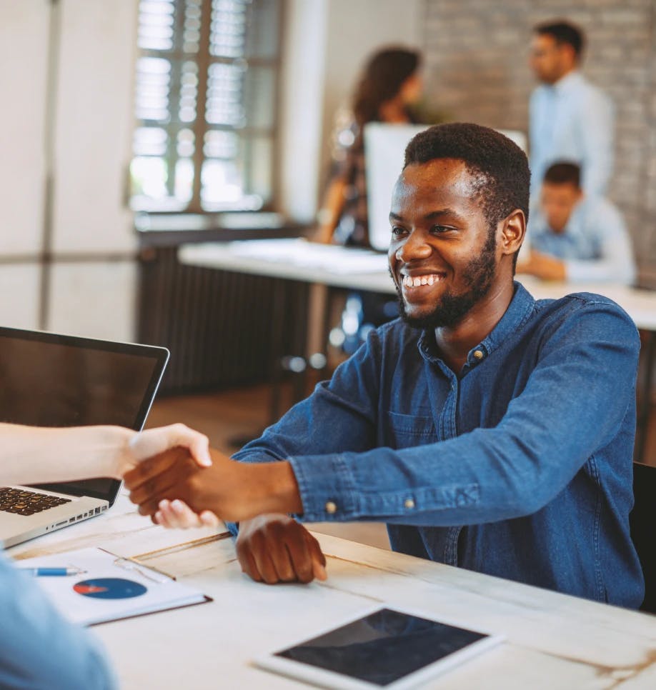 Man smiling shaking hands with someone at a desk