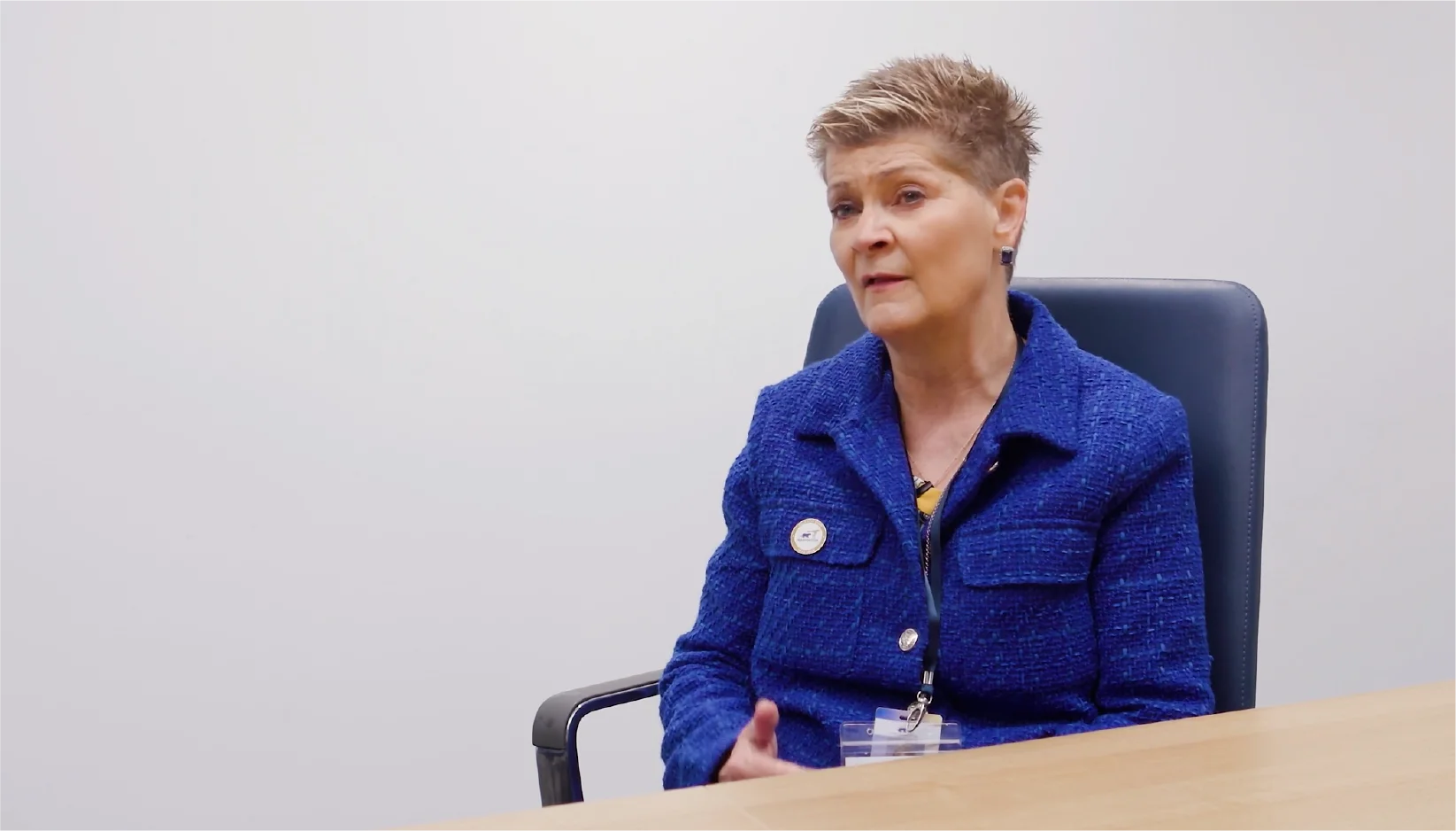 A woman sitting in a chair at a conference table being interviewed