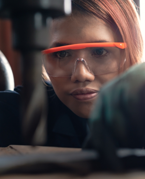 Intern wearing protective eyewear while using a hand drill